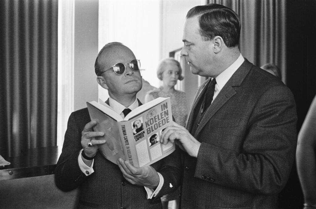 Imagen de Truman Capote sosteniendo un ejemplar de su libro A sangre fría, considerado un true crime